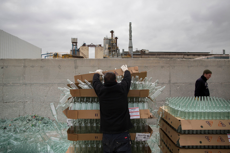 Workers unload defective glass bottles to be recycled